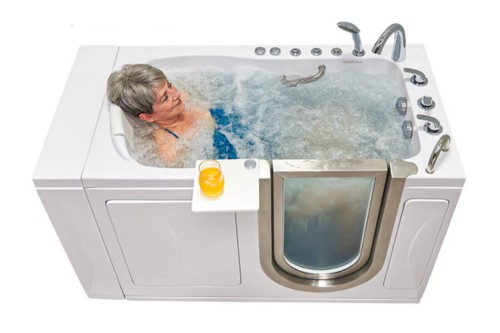 Senior woman relaxing in a walk-in tub with water jets on, enjoying a therapeutic soak with a drink on the side