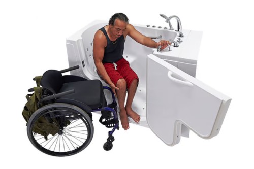 Man transferring from a wheelchair into a walk-in tub with an open L-shaped door for easy accessibility